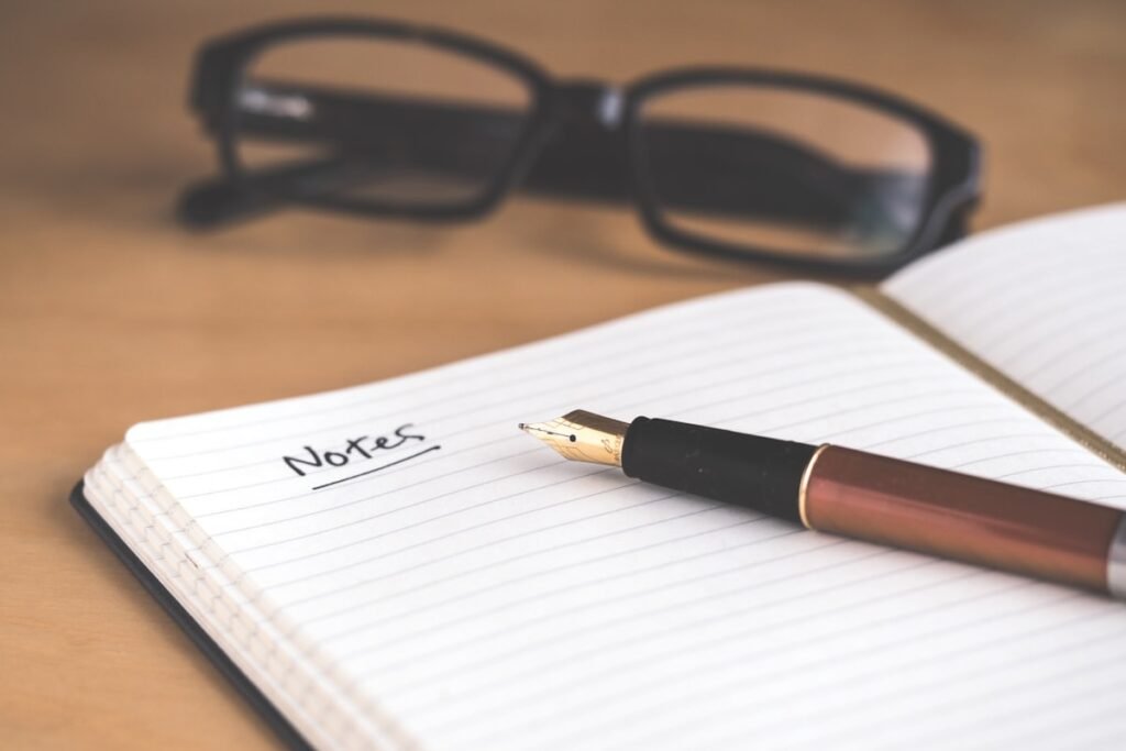 Woman writing in a journal at a wooden desk with coffee nearby